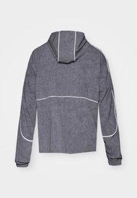 Gray hooded jacket with a textured finish. Features white piping along seams and elastic cuffs. Designed with a cropped silhouette.