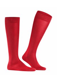Calze rosse al ginocchio realizzate in un materiale liscio e elastico. Il design presenta un colore uniforme con un bordo a coste nella parte superiore.