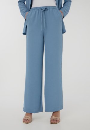 Pantaloni ampi blu chiaro realizzati in tessuto testurizzato, con vita elastica e cordoncino, e tasche laterali.