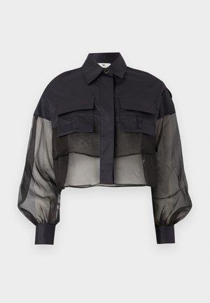 Musta lyhyt paita läpikuultavilla pitkillä hihoilla, kahdella etutaskulla, joissa kohokuvioidut kirjaimet "E" ja "F", sekä terävä kaulus, jossa yksi nappi.