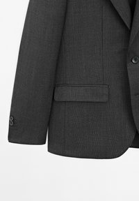 Blazer grigio scuro in tessuto strutturato, con rever a lancia, due bottoni sul polsino e una tasca al petto singola senza decorazioni visibili.