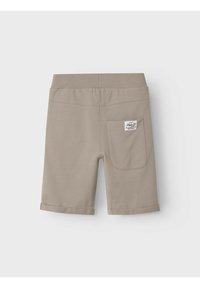 Pantalones cortos de algodón beige con dobladillo plegado, cinturilla elástica y un solo bolsillo trasero con una etiqueta. Textura suave con un diseño minimalista.