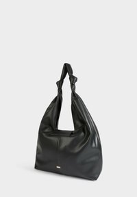 Borsa in pelle nera con un design morbido e sformato. Presenta manici superiori annodati e una texture liscia, con un piccolo accento metallico sul davanti.