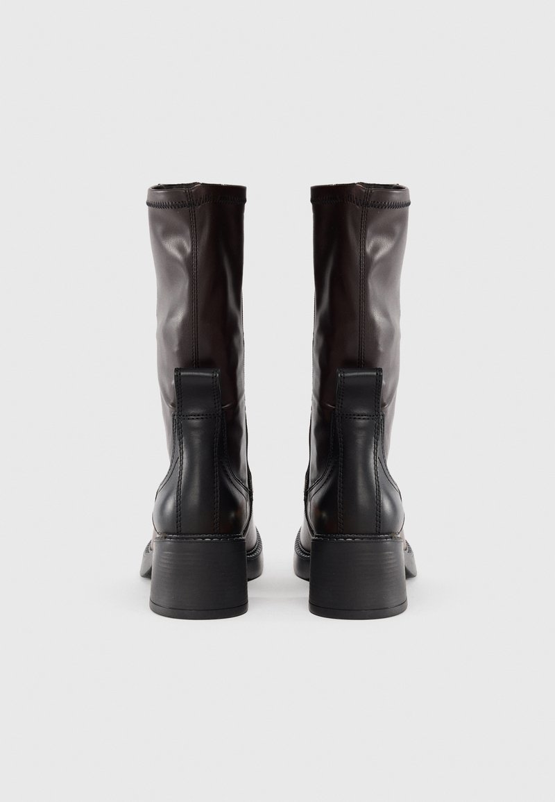 Bottes en cuir marron montantes, à bout rond, avec un talon bloc robuste et des coutures décoratives à l'arrière et sur les côtés.