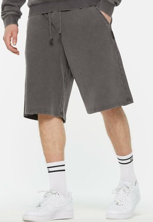 Gray cotton blend shorts with a relaxed fit, side pockets, drawstring waist, and a knee-length cut paired with white socks and sneakers.