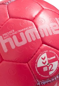 Rosa handboll med hexagonala paneler. Har Hummel-märkning, en texturerad yta och tryckta tryckanvisningar på en panel.