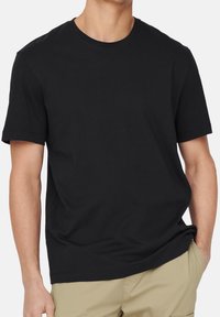 Sort bomulds T-shirt med rund halsudskæring og korte ærmer. Har en afslappet pasform og glat tekstur, ingen mønstre eller synlige logos.