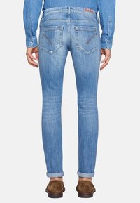 Jasnoniebieskie dżinsy o slim fit, z średnim stanem, pięcioma kieszeniami i podwiniętymi mankietami. Subtelne przetarcia i kontrastowe szwy.