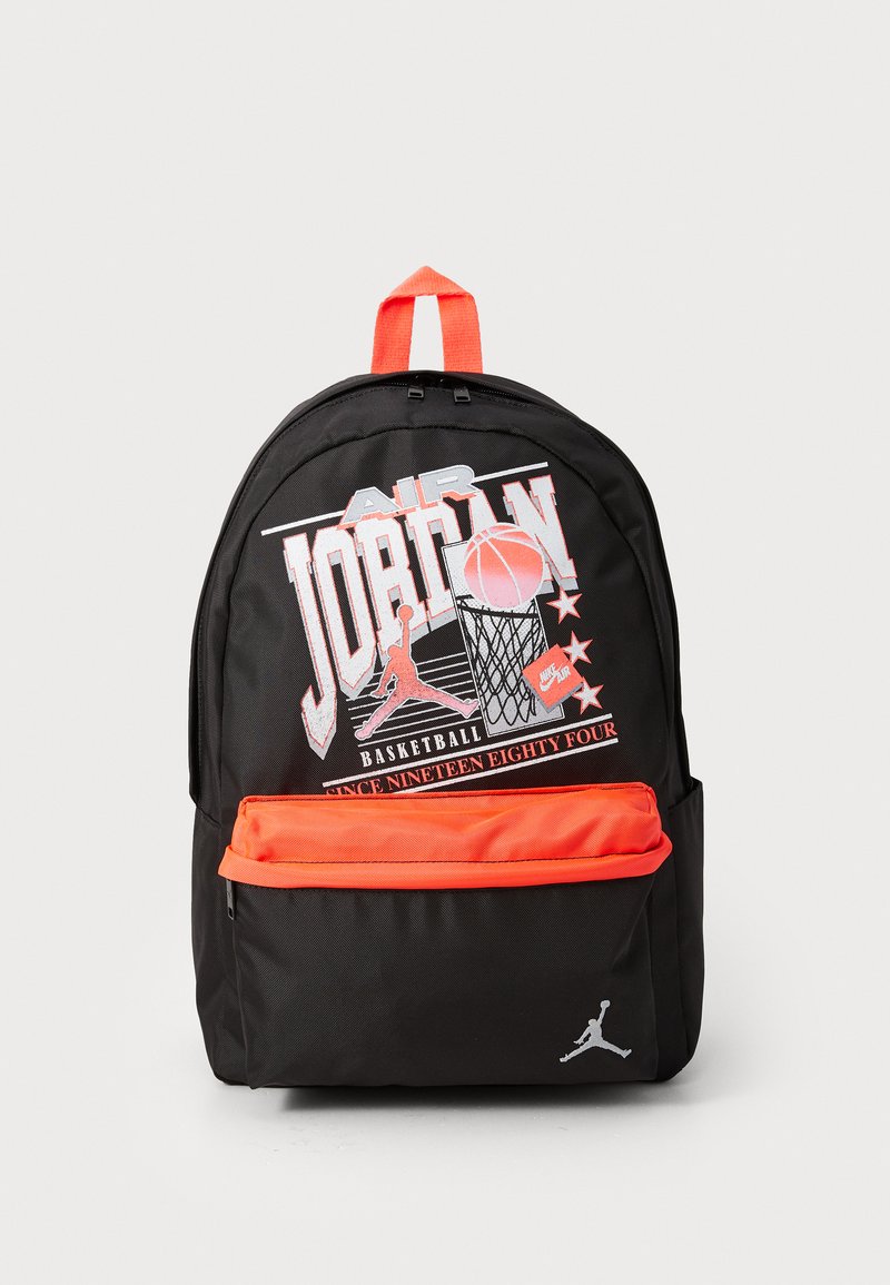Sac à dos noir avec une poche zippée orange et une poignée supérieure. Il présente un motif graphique emblématique avec un motif de basket-ball et un logo.