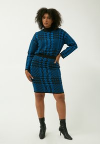 Suéter azul con patrón y falda ajustada a juego. El suéter tiene mangas largas y un escote alto, mientras que el conjunto cuenta con una cinturilla negra y detalles en negro.