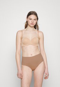 Nude strapless bra with smooth cups, lightly padded and a sleek design. Paired with seamless, high-waisted brown briefs.