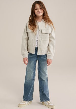 Lys grå fleecejakke med to brystlommer, ribbede manchetter og en afslappet pasform, kombineret med blå vide jeans og beige sneakers.