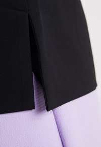 Czarny i lawendowy dział odzieżowy z gładkim materiałem o wyraźnym brzegu i delikatnym wzorem tekstury, uwypuklający kontrast kolorów.