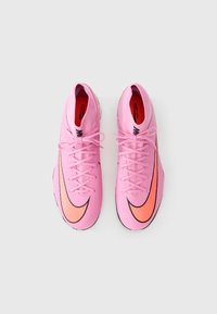 Pink athletic shoes with a textured upper, black accents, and an orange swoosh design. Features laces and a rounded toe shape.