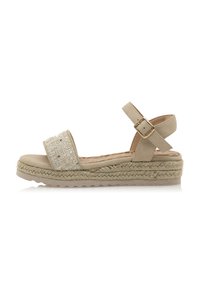 Sandalia de esparto beige con una correa de glitter texturizado, un hebilla ajustable en el tobillo y una suela de plataforma de yute trenzado.