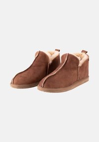 Bottines en daim marron avec une douce doublure en shearling beige, présentant un design de couture et une languette à l'arrière pour un enfilage facile. Semelle en caoutchouc plate.