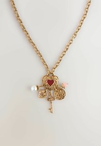 Goldene Halskette mit einem zentralen Anhänger im filigranen Design, Herzformen, einem roten Akzent und einem Schlüsselanhänger.