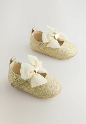 Goldene Glitzer-Ballettschuhe mit einer cremefarbenen Schleife, runder Zehenpartie und verstellbarem Riemen. Glatte Textur mit einem weichen Futter.