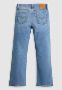 Jean denim bleu clair à coupe droite, doté d'un design à cinq poches, d'un patch en cuir à la taille et de détails de couture visibles.