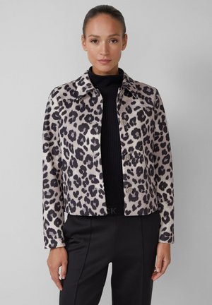 Leopard-print cropped jacket in beige and black, featuring a collared neck and button closure, worn over a black ribbed top.