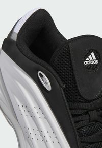 Scarpa sportiva nera con tomaia in rete, colletto imbottito e dettagli bianchi. Logo distintivo sulla linguetta e dettagli perforati ai lati.