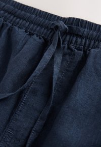 Marineblaue Leinen-Shorts mit elastischem Bund und Kordelzug, mit glatter Textur und lockerem Schnitt. Die Umrissnähte sind sichtbar.