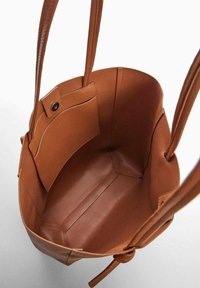 Brązowa skórzana torba tote z długimi uchwytami, charakteryzująca się gładką strukturą i jedną wewnętrzną kieszenią zamykaną na zatrzask.