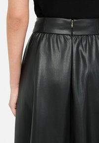 Gonna nera in ecopelle con design a pieghe, caratterizzata da una consistenza liscia, cintura larga e chiusura con zip sul retro.