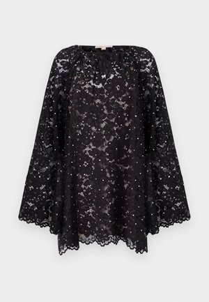 Black lace poncho with scalloped hem, featuring a gathered neckline and intricate floral patterns. Dotted embellishments throughout the fabric.