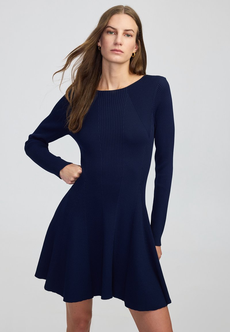 Navyblauwe geribde jurk met lange mouwen en een aansluitend bovenlijfje, uitlopend in een skaterrokontwerp; gladde textuur en effen kleur.