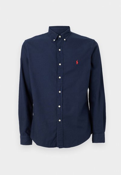 Temno moder gumbasti srajca iz bombaža, z klasičnim ovratnikom, dolgimi rokavi in majhnim rdečim logotipom na levem prsnem delu.