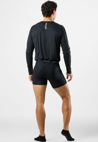 Black long-sleeve shirt and black ribbed boxer shorts. The shirt has a tag at the back, and the shorts feature a branded waistband.