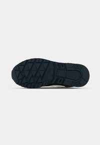 Black rubber outsole with a multi-directional tread pattern, designed for traction and durability, featuring a smooth section near the heel.