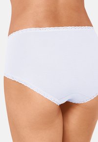 Witte katoenen hipster slip met kantafwerking bij de taille en beenopeningen, met een gladde textuur en naadloos ontwerp.