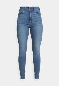 Jeans skinny de talle alto en azul, con bolsillos frontales, cierre de dos botones y piernas ajustadas sobre un fondo blanco liso.