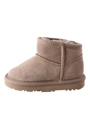 Bottine beige en daim pour enfants avec doublure intérieure douce et semelle plate en caoutchouc, vue de côté sur fond blanc.