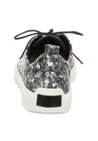 Black and white patterned sneaker with a textured upper, rounded toe, and a white rubber sole. Features black laces and a red accent at the heel.