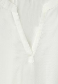 White blouse with a V-neck and a small button detail at the neckline. Soft, smooth fabric with a subtle sheen and no patterns.