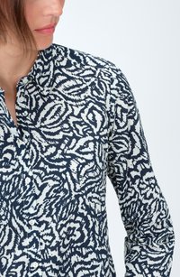 Camisa de botones con un patrón floral abstracto en azul marino y blanco, diseño con cuello, mangas largas y textura de tela suave.