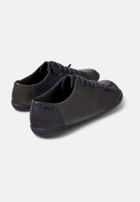 Scarpe in pelle grigio scuro con punta arrotondata, cuciture sottili e design con lacci. Profilo basso con un accento sul tallone di colore più chiaro.