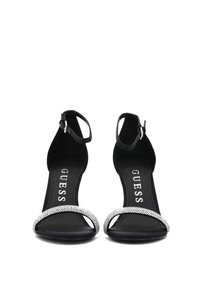 Sandalias de tacón negro con material texturizado, que cuentan con una tira de strass brillante a lo largo del dedo del pie y una correa ajustable en el tobillo.