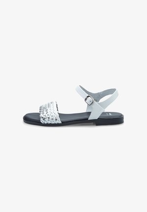 White woven flat sandals with a rounded toe, adjustable ankle strap, and a smooth black sole. Features a braided texture on the upper.
