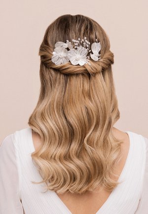 Haaraccessoire mit zarten weißen Blumen und Perlen, das vor welligem, hellbraunem Haar platziert ist. Entworfen mit kunstvollen Details und Texturen.