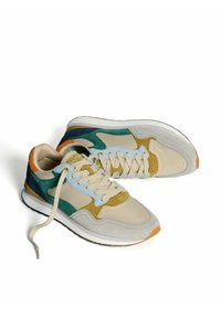 Zapatillas de ante beige con acentos en verde, azul y naranja, que cuentan con un acabado texturizado, cordones en contraste y una suela acolchada.