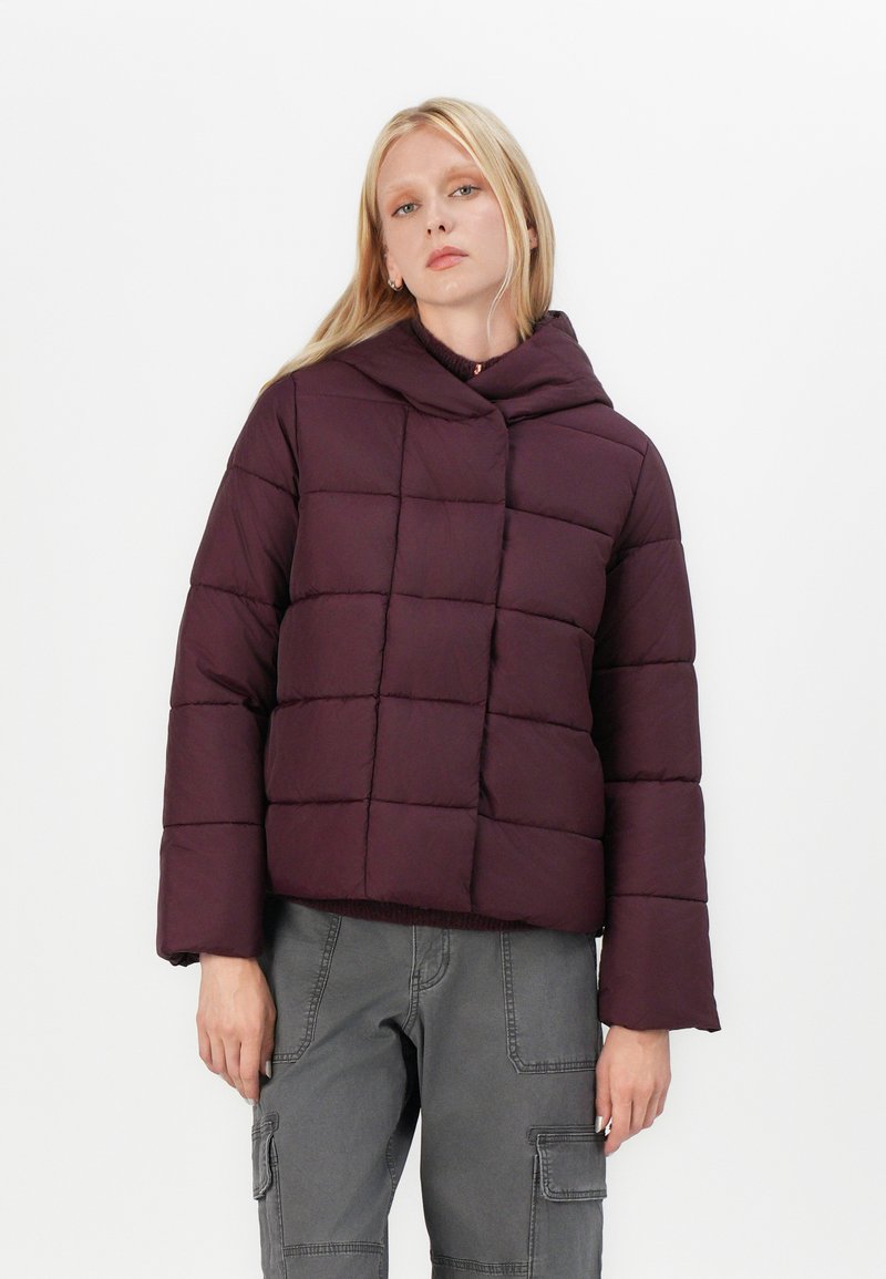Giacca imbottita viola con cappuccio, caratterizzata da un design squadrato e quadrati cuciti. Maniche lunghe e silhouette corta.
