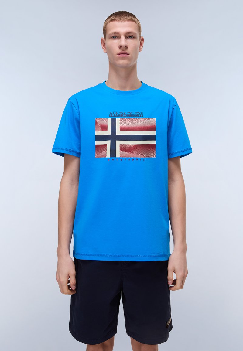 Modrá bavlněná tričko s potiskem norské vlajky v červené, bílé a modré barvě. Hladký kulatý výstřih a volný střih.