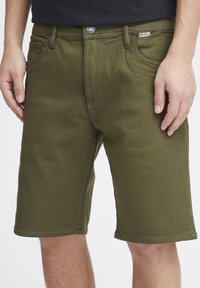 Olivgrüne Baumwollshorts mit geradem Schnitt, Fronttaschen und Knopfverschluss; glatte Textur und saubere Nähte.