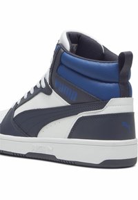 Zapatillas de caña alta con parte superior de cuero en tonos azul marino, blanco y azul. Incluyen un collar acolchado, cordones blancos y detalles con el logo de Puma.