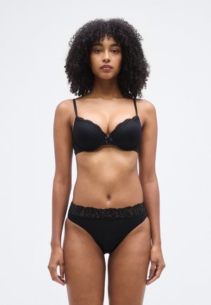 Ensemble de lingerie noire comprenant un soutien-gorge rembourré orné de dentelle et de fines bretelles, assorti à une culotte taille haute avec une ceinture en dentelle.