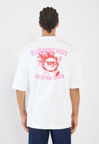 White short-sleeve t-shirt featuring a colorful graphic on the back with the text "BURNIN' HOT" above a cartoon character and "KEEPIN' COOL" below.